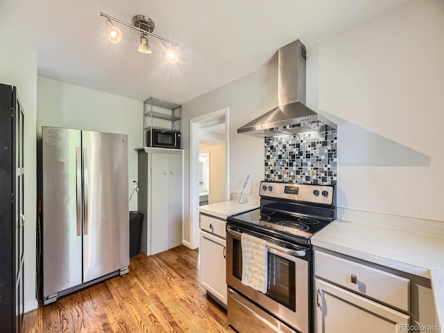 835 Knox Ct, Denver, CO 80204 - kitchen featuring stainless steel appliances, wall chimney range hood, track lighting, light wood-style flooring, and light countertops