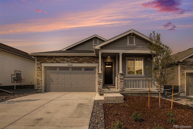 view of front of property with a porch, concrete driveway, stone siding, and an attached garage