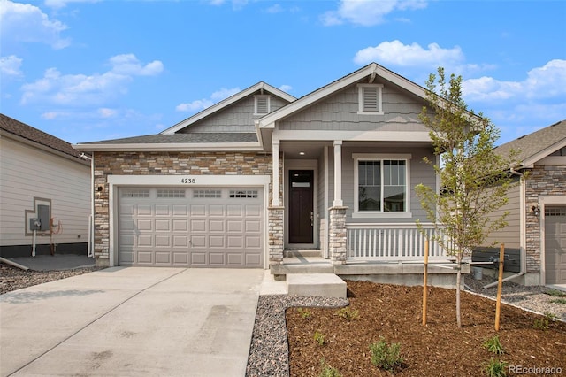 view of front of home featuring an attached garage, stone siding, a porch, and concrete driveway