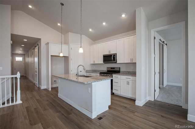 kitchen featuring light stone countertops, a center island with sink, stainless steel appliances, sink, and white cabinetry