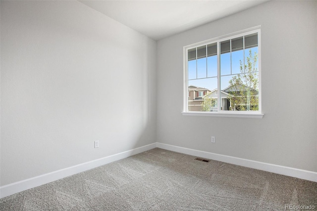 spare room featuring carpet floors, visible vents, and baseboards