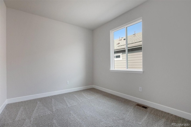 carpeted spare room featuring baseboards and visible vents