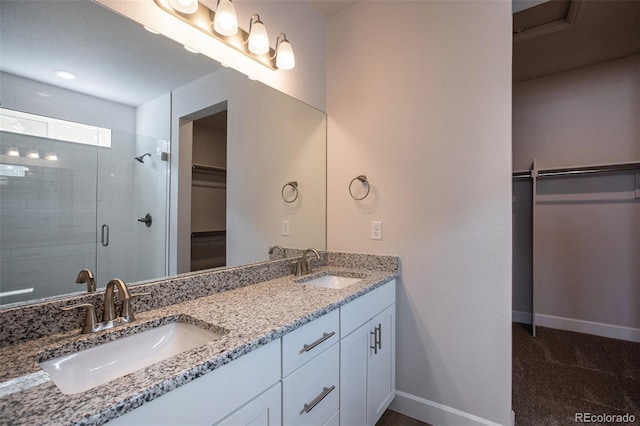 full bath featuring double vanity, a shower stall, baseboards, and a sink