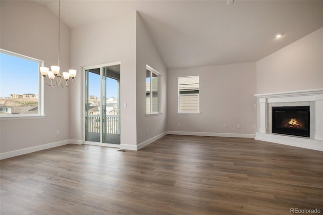 unfurnished living room with baseboards, visible vents, wood finished floors, a fireplace, and a chandelier