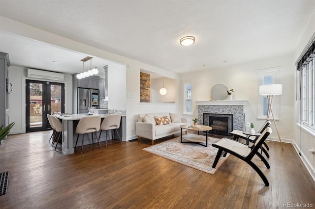 living room with dark hardwood / wood-style floors, a textured ceiling, french doors, and a wall mounted AC