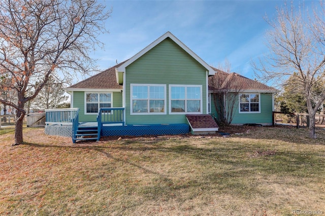 rear view of property featuring a deck, a yard, roof with shingles, and fence