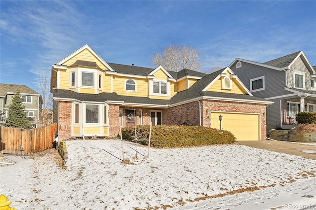 traditional-style home with brick siding, fence, driveway, and an attached garage