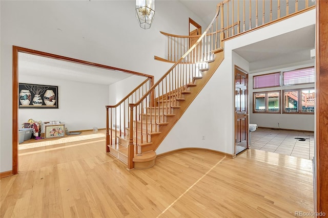 stairs featuring a high ceiling, wood finished floors, and baseboards