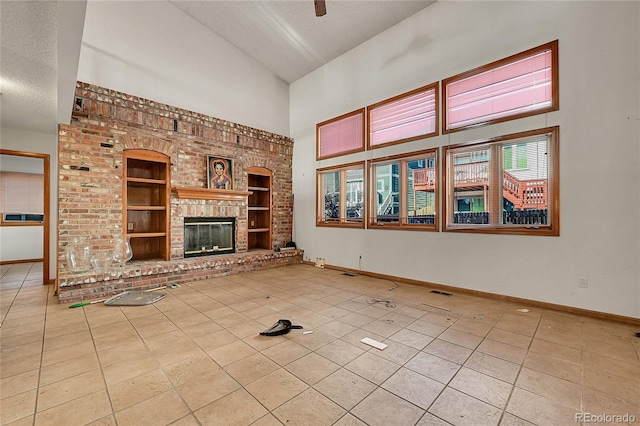 unfurnished living room with built in features, a fireplace, light tile patterned flooring, a textured ceiling, and baseboards