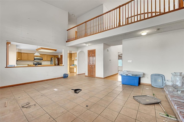 unfurnished living room with arched walkways, a high ceiling, light tile patterned flooring, and baseboards