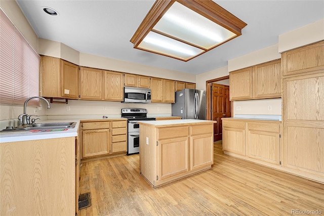 kitchen with a sink, light countertops, appliances with stainless steel finishes, light wood-type flooring, and a center island