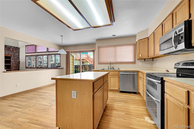 kitchen featuring a sink, light countertops, appliances with stainless steel finishes, a center island, and decorative light fixtures