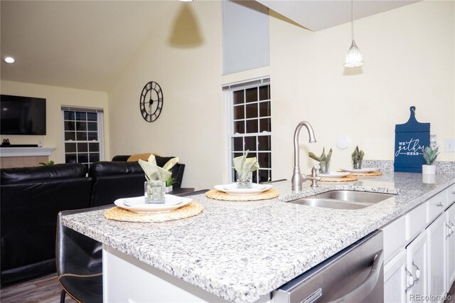 kitchen featuring white cabinetry, dishwasher, sink, hanging light fixtures, and light stone countertops