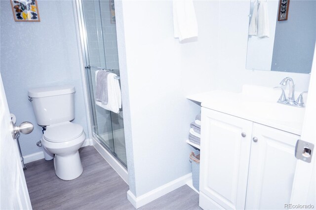 bathroom featuring hardwood / wood-style flooring, toilet, vanity, and a shower with shower door