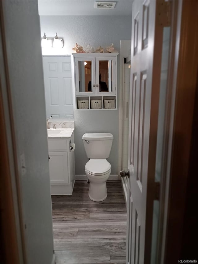 bathroom featuring vanity, wood-type flooring, and toilet