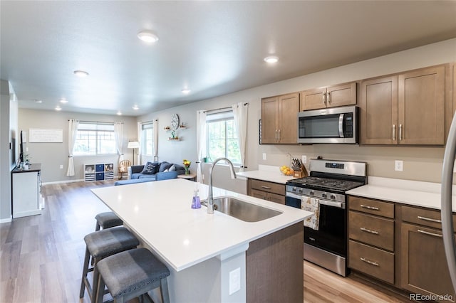 12743 Ulster St, Thornton, CO 80602 - kitchen with stainless steel appliances, light wood-type flooring, healthy amount of natural light, a kitchen breakfast bar, and recessed lighting