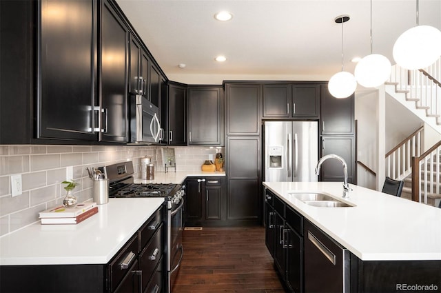 2559 S Kendrick St, Lakewood, CO 80228 - kitchen with decorative backsplash, appliances with stainless steel finishes, a sink, dark wood-type flooring, and an island with sink