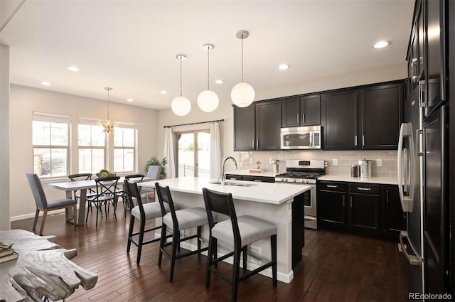 2559 S Kendrick St, Lakewood, CO 80228 - kitchen with a kitchen bar, light countertops, a sink, appliances with stainless steel finishes, and backsplash