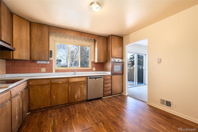 kitchen featuring stainless steel dishwasher, dark hardwood / wood-style floors, oven, and tasteful backsplash