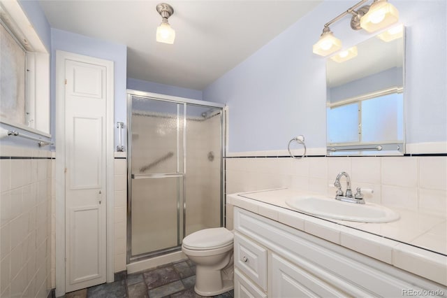 bathroom with an enclosed shower, vanity, tile walls, and toilet