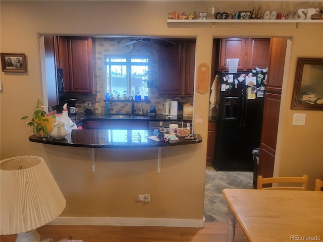 2190 S Holly St Unit 213, Denver, CO 80222 - kitchen featuring black refrigerator with ice dispenser, dark countertops, a peninsula, a breakfast bar, and backsplash