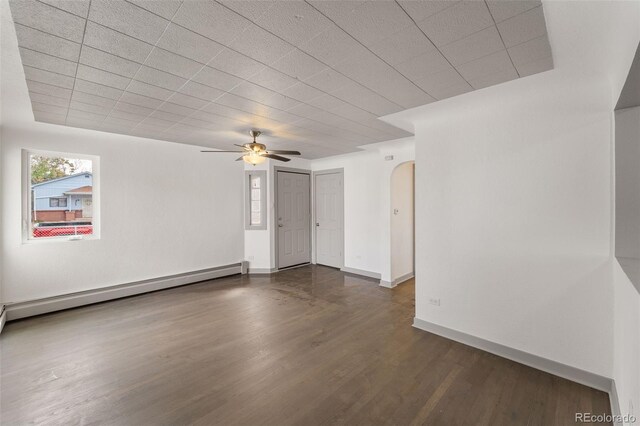 empty room with baseboard heating, ceiling fan, and dark wood-type flooring