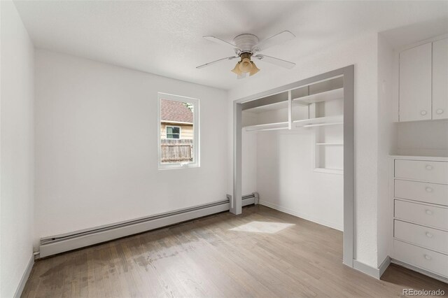 unfurnished bedroom with a baseboard radiator, a closet, ceiling fan, and light wood-type flooring