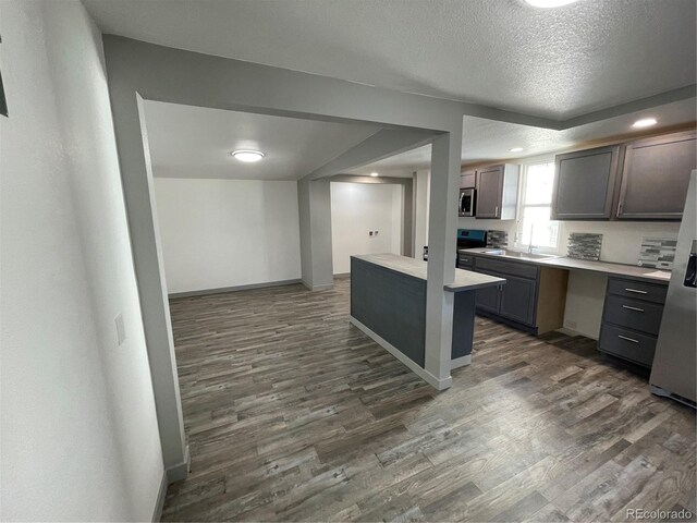 kitchen featuring dark brown cabinets, stainless steel appliances, dark hardwood / wood-style floors, and a textured ceiling