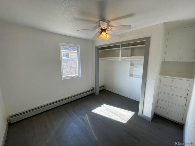 unfurnished bedroom with ceiling fan, baseboard heating, a textured ceiling, dark hardwood / wood-style flooring, and a closet