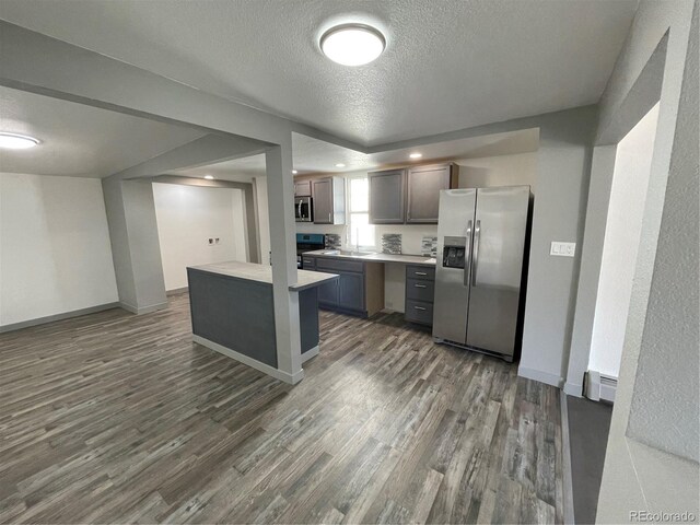 kitchen with a baseboard radiator, stainless steel appliances, dark hardwood / wood-style flooring, and a textured ceiling