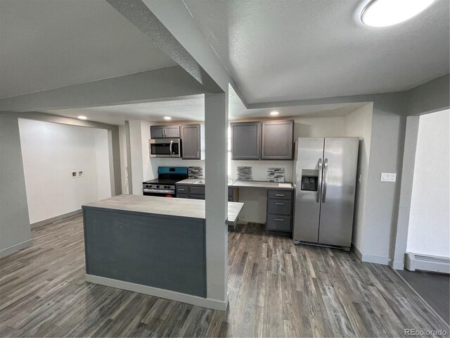 kitchen with dark wood-type flooring, stainless steel appliances, baseboard heating, and a textured ceiling