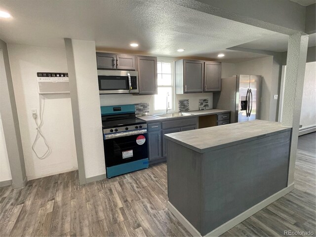 kitchen with appliances with stainless steel finishes, sink, hardwood / wood-style floors, and a textured ceiling