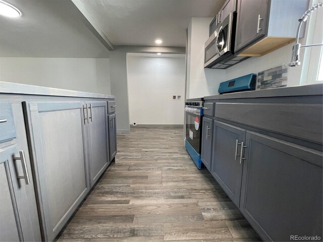 kitchen with stainless steel appliances, dark hardwood / wood-style flooring, and gray cabinetry