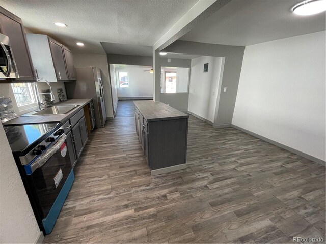 kitchen with stainless steel range with electric stovetop, dark wood-type flooring, a center island, and a textured ceiling