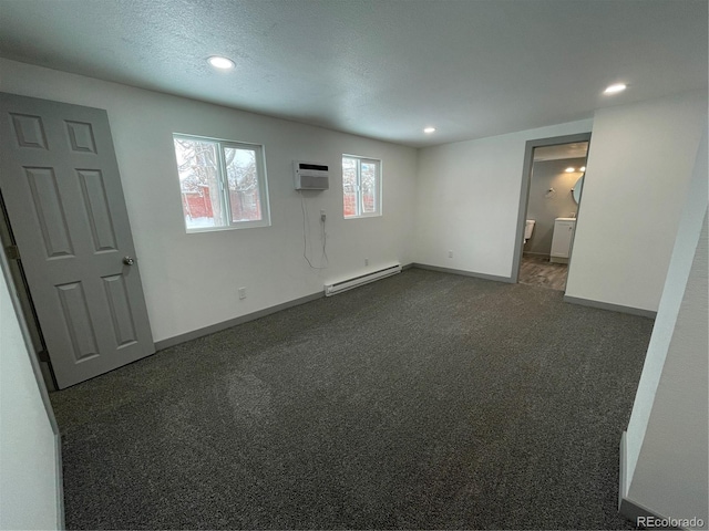 carpeted empty room with an AC wall unit, a baseboard heating unit, and a textured ceiling