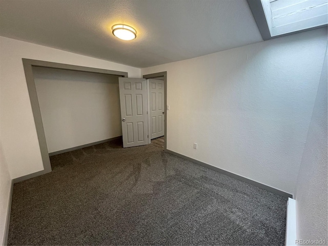 unfurnished bedroom with dark colored carpet, a textured ceiling, and a closet