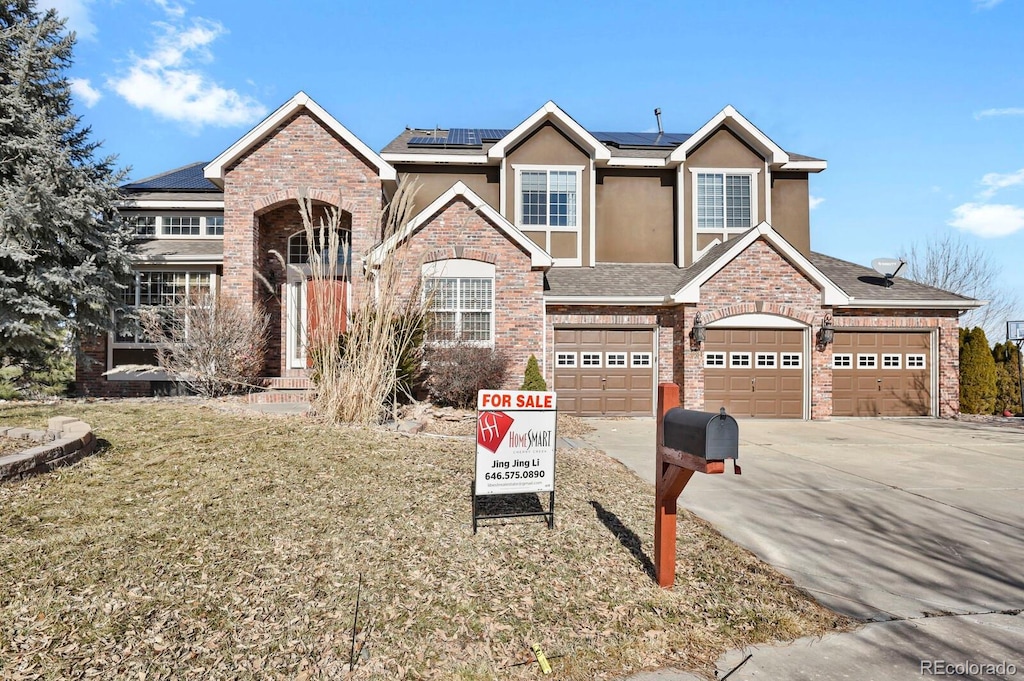 view of front of property featuring a garage, a front yard, and solar panels