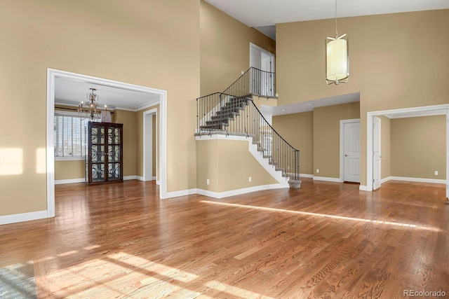 interior space with hardwood / wood-style floors, a towering ceiling, and an inviting chandelier