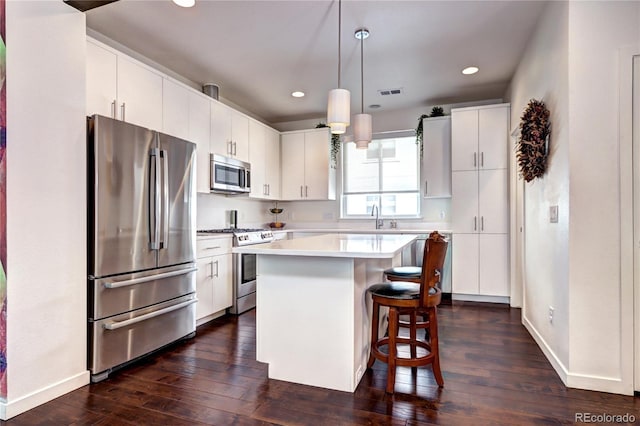 852 Kalamath St, Denver, CO 80204 - kitchen with appliances with stainless steel finishes, dark wood-style floors, a breakfast bar area, light countertops, and a kitchen island