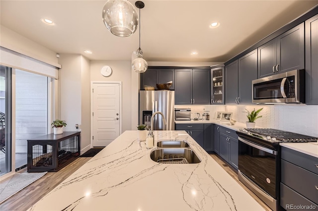 6211 Stable View St, Castle Pines, CO 80108 - kitchen featuring appliances with stainless steel finishes, glass insert cabinets, tasteful backsplash, pendant lighting, and light stone counters