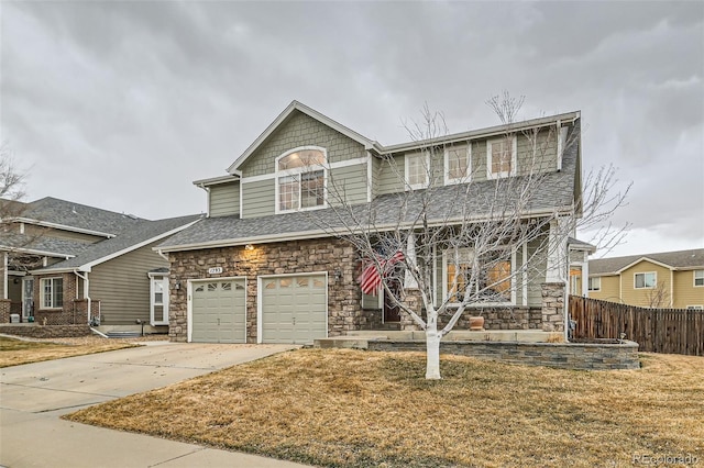 view of front of house with a garage, concrete driveway, stone siding, fence, and a front lawn