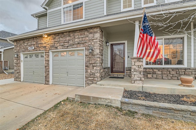 doorway to property with a garage, stone siding, and driveway