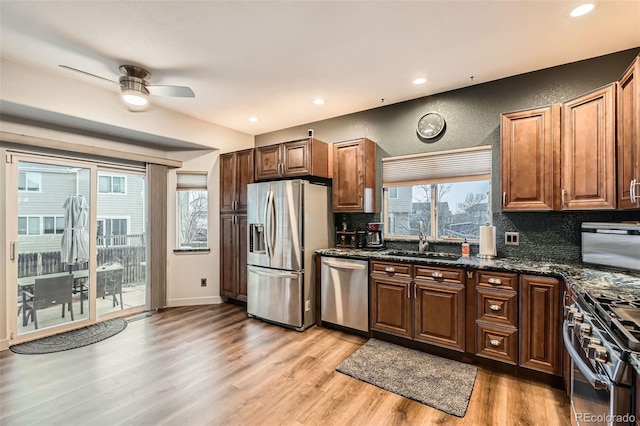 kitchen with a textured wall, light wood-style flooring, stainless steel appliances, a sink, and tasteful backsplash