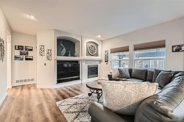 living area with recessed lighting, visible vents, a tiled fireplace, wood finished floors, and baseboards