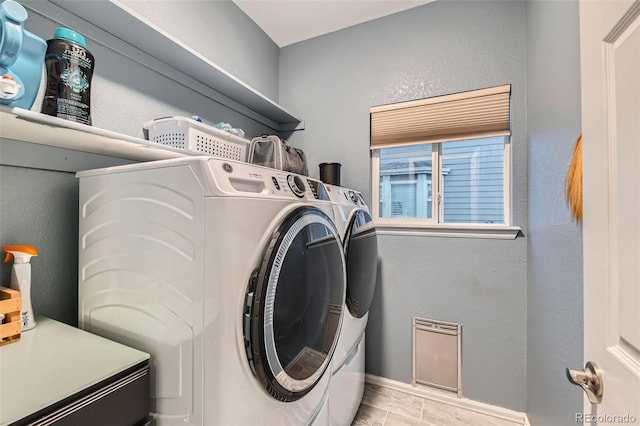 washroom featuring laundry area, baseboards, washer and dryer, and a textured wall