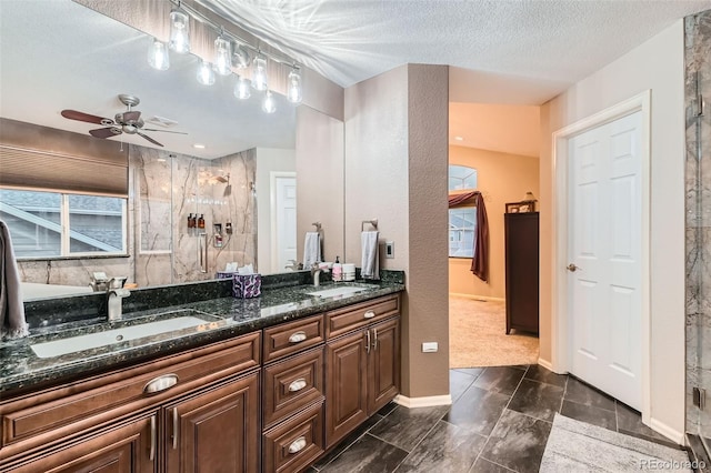 bathroom featuring a walk in shower, double vanity, a textured ceiling, and a sink