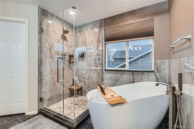 bathroom featuring a textured ceiling, a marble finish shower, tile walls, and a freestanding bath