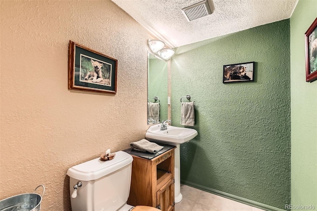 bathroom with visible vents, a textured wall, toilet, a textured ceiling, and a sink