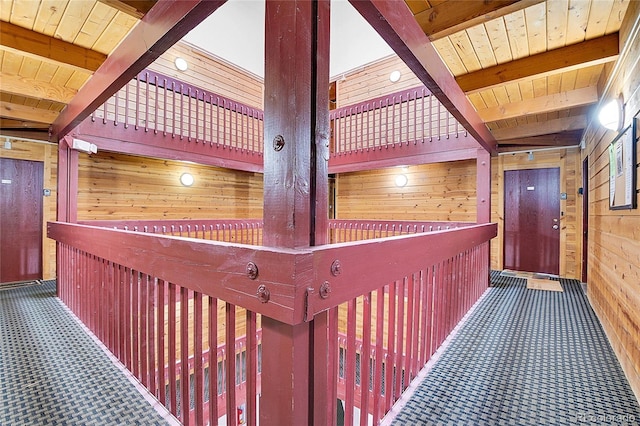 hall with wood walls, beam ceiling, wooden ceiling, and carpet