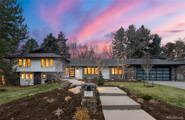 view of front of house featuring a yard, stone siding, a garage, and driveway